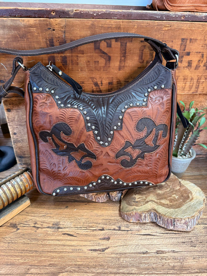 Brown leather handbag with chocolate tooled panels, silver studs, and black strap