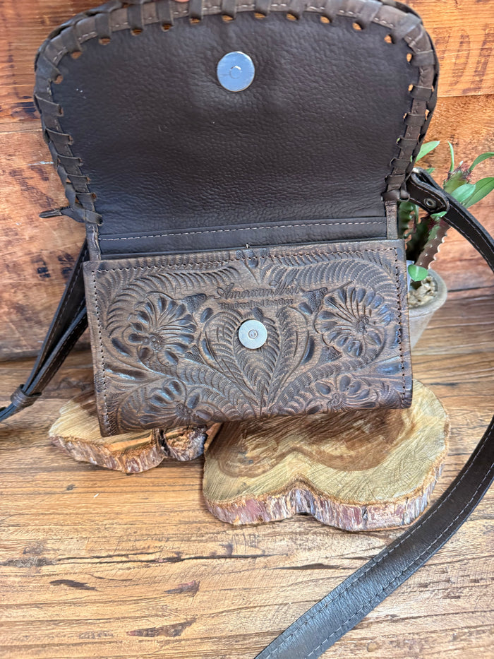 Dark brown crossbody purse with top compartment and embossed floral flap, shown open