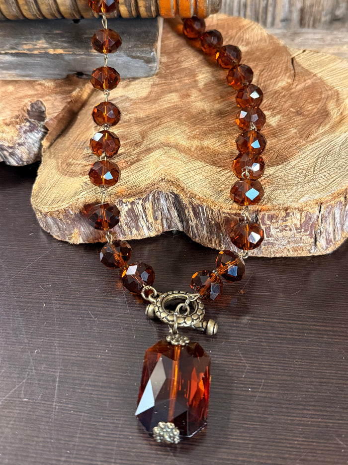 Amber crystal bead necklace close-up with faceted pendant and metal charm centerpiece