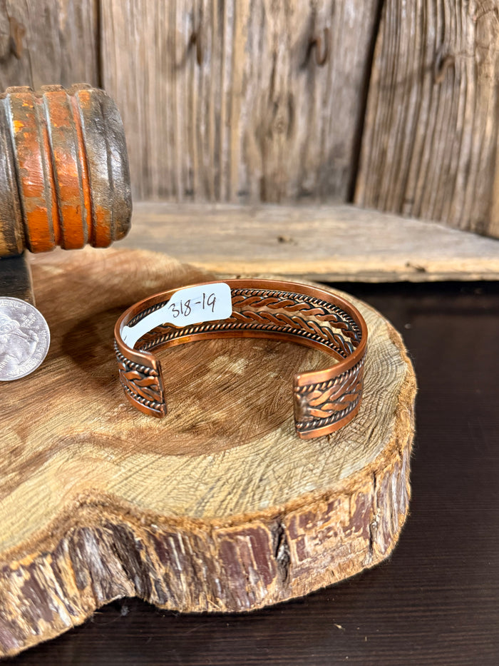 Woven copper cuff bracelet with stamped inside marking 318-19 and braided wave trim
