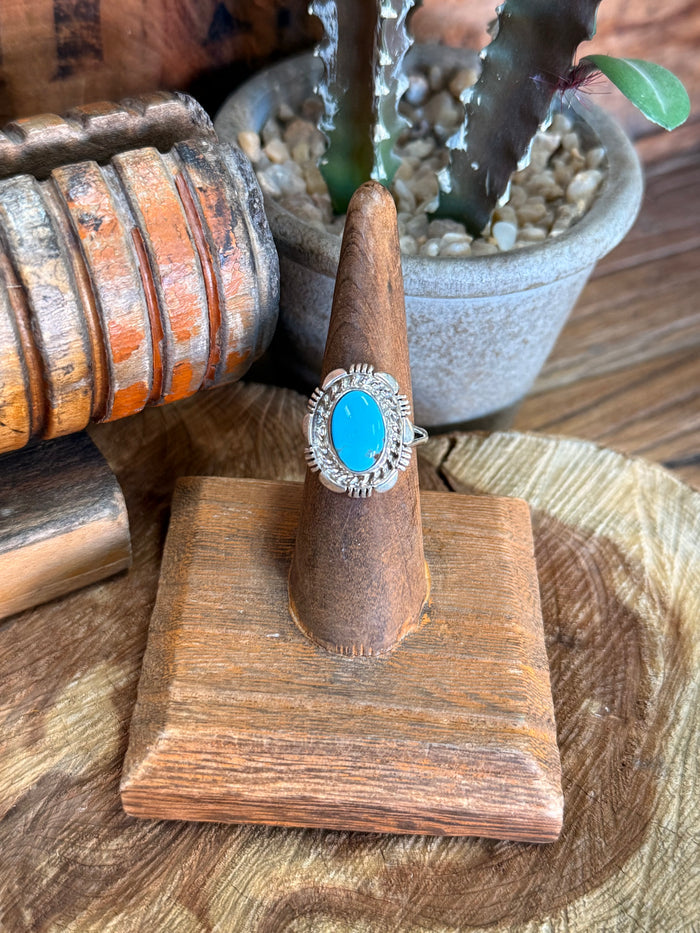 Oval turquoise cabochon silver ring with ornate bezel and rope-edge setting