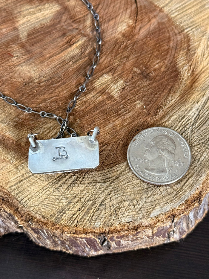 Sterling silver pendant back with engraved stamp on chain, with coin for scale