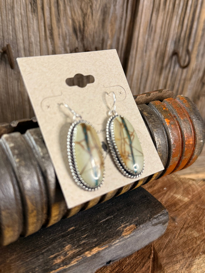 Silver fishhook dangle earrings with oval turquoise ribbon stones in textured beaded frame