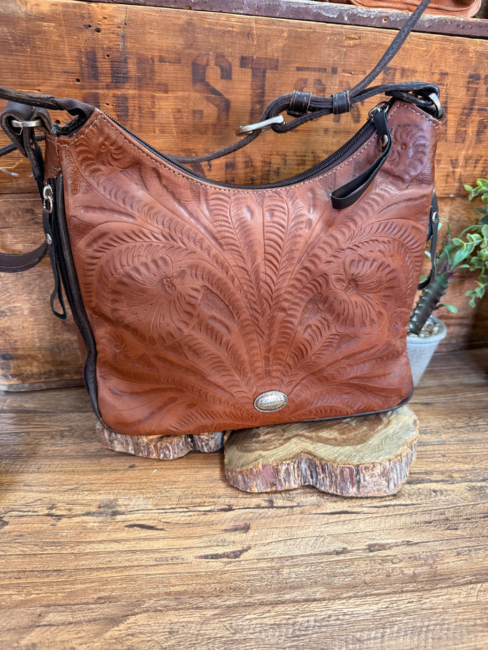 Brown leather shoulder handbag with carved leaf tooling, silver stud accents, side tassels