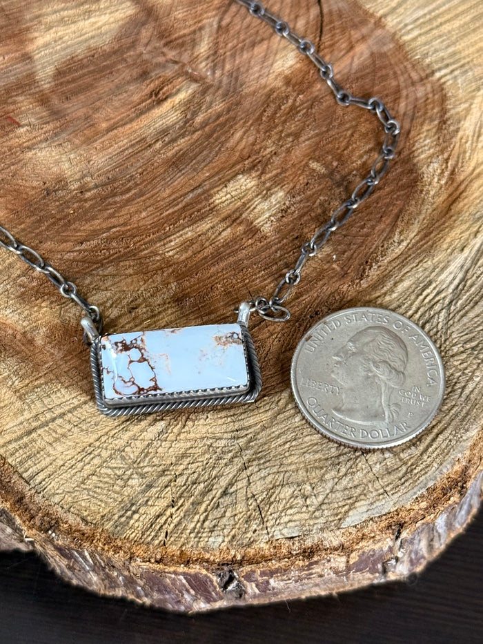 Rectangular sterling silver pendant with blue wild horse scene, shown with coin for size