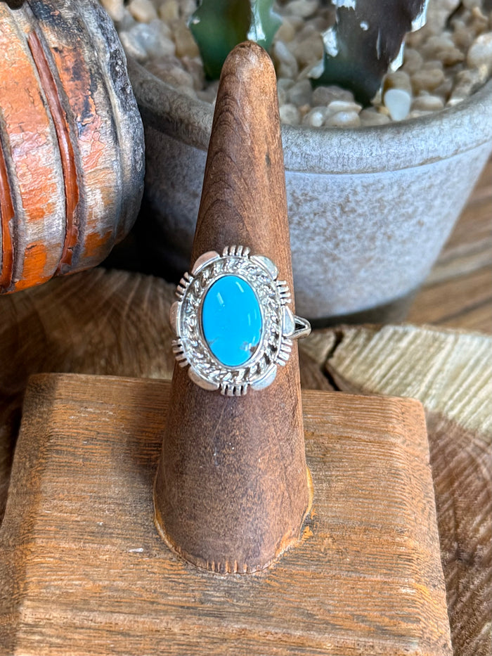 Oval blue turquoise silver ring with detailed oval frame, shown on display stand