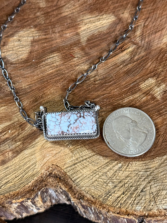 Sterling silver wild horse necklace with rectangular pendant next to coin for size