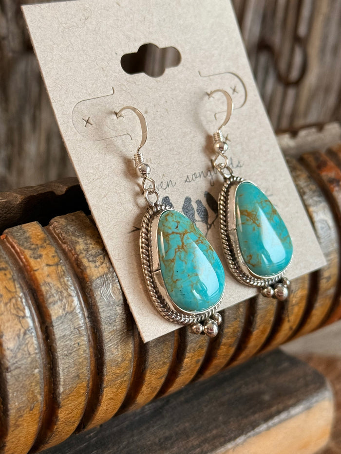 Turquoise teardrop fishhook earrings with dangling silver bead charms and frames