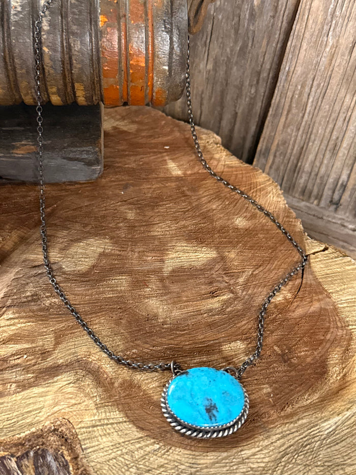 Turquoise pendant necklace with large oval blue turquoise cabochon and dark chain.
