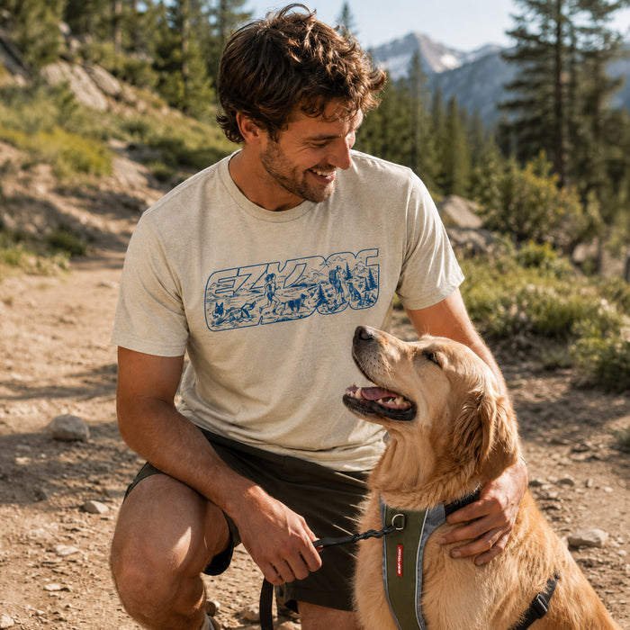 A male model on a pacific northwest trail is wearing the EzyDog adventure t-shirt while petting his dog that's wearing an EzyDog X-Link Harness