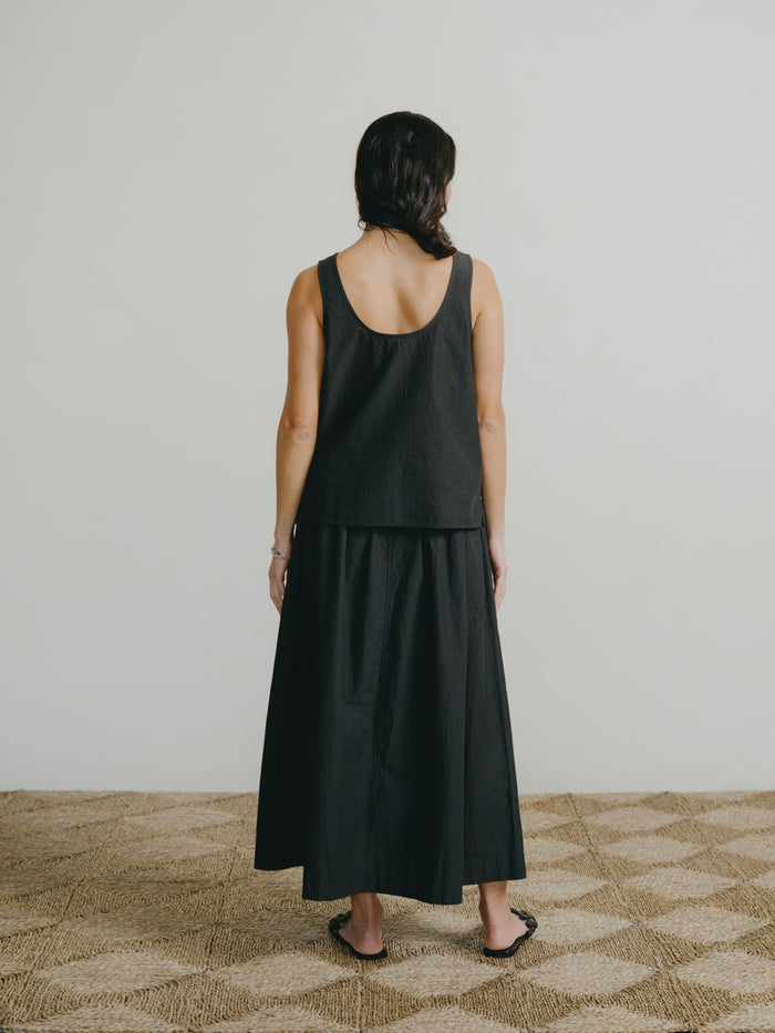 Person wearing a black sleeveless top and skirt set on a neutral background