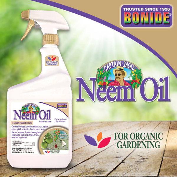 A quart bottle of Bonide - Captain Jacks™ Neem Oil Ready-to-Use (All Delivery Options) rests on wood, highlighting its use in organic gardening and pest control since 1926, set before a lush green, leafy background.