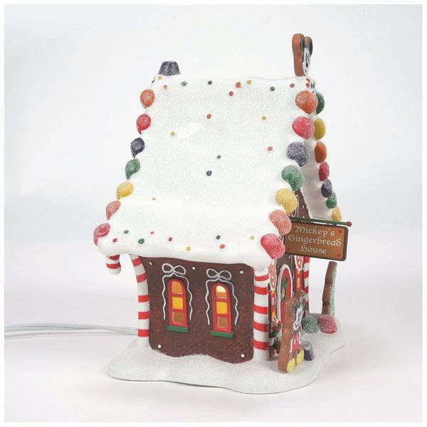 The Department 56 - Mickey’s Gingerbread House, part of our festive Christmas décor, is adorned with colorful gumdrops and peppermint sticks. Its snowy roof sparkles with multicolored sprinkles, complemented by a charming sign reading Mickey’s Gingerbread House.