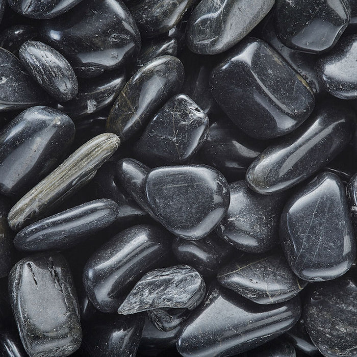 A close-up of Exotic Pebbles - Polished Black Pebble (5 lb.), featuring smooth, shiny black stones from Available for Pickup & Delivery, closely packed together and reflecting light.