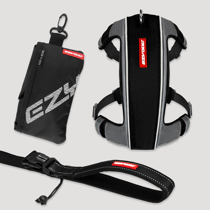 Black and gray dog harness with red label on a light gray background