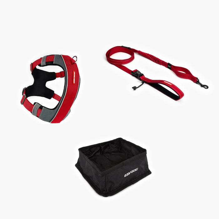 Red and black dog harness, leash, and black foldable bowl on a white background