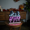 The Infinity Light - Spooky Ghosts, featuring a glowing LED sign with three cartoon ghosts and SPOOKY in dripping letters, is perfect Halloween décor. It sits on a stool amid autumn decorations like pumpkins and leaves atop a wooden cabinet. Available for Pick-up & Delivery.