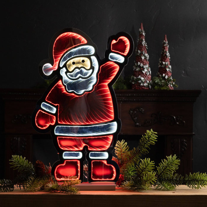 The 23” Infinity Light – Waving Santa from Available for Pick-Up & Delivery enhances your decor with a neon-style glow in red, white, and yellow. Set on a wood surface amid cone decorations and greenery, it brings festive cheer against a dark backdrop.