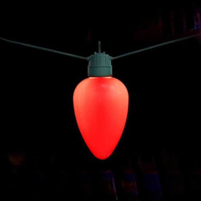 The Jumbo LED Lit Bulb - Red by Available for Pick-Up & Delivery glows brightly on a green wire, making a striking display against a dark background.