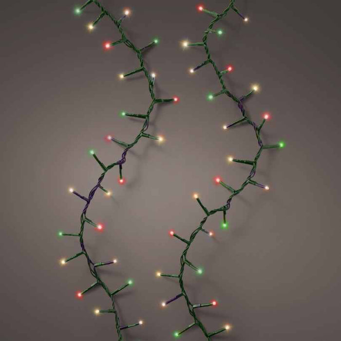 Two strands of LED 1000 ct. Compact String Lights Multi-Colored by Available for Pick-Up & Delivery are draped in a zigzag pattern against a gray background, their festive red, green, yellow, and white glow creating lively holiday ambiance.