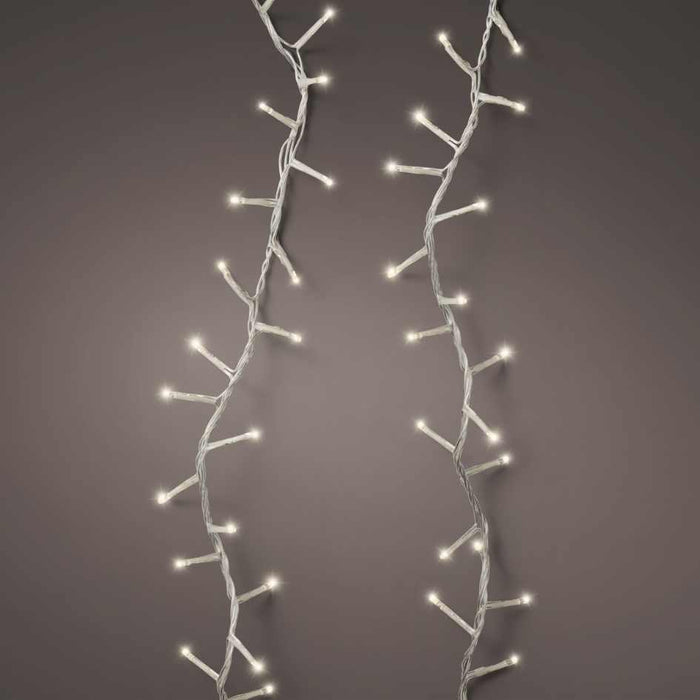 The LED 1000 ct. Compact String Lights Twinkle Warm White by Available for Pick-Up & Delivery emit a warm glow, with branch-like offshoots softly illuminating a plain, neutral gray background.