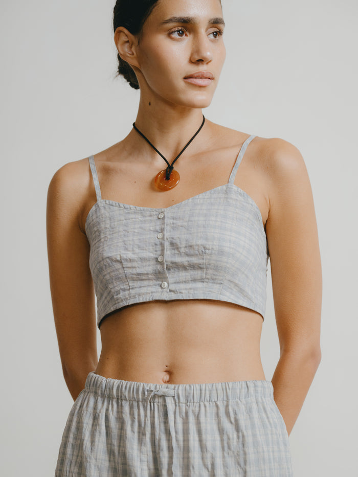 Woman wearing a gray crop top and pants with a plain background
