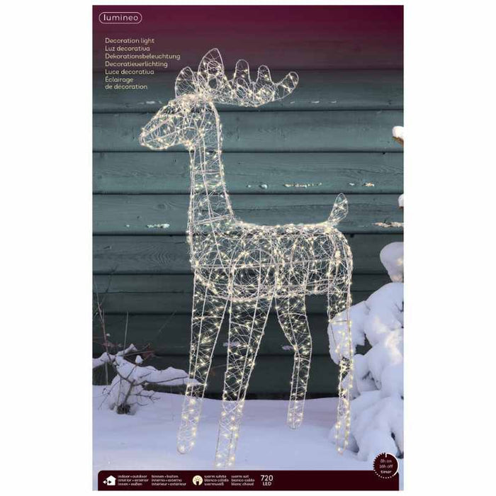 The Micro LED Lit Reindeer – Warm White Lights – Flashing Effect from Available for Pick-Up & Delivery adds enchanting holiday charm to your outdoor décor, glowing beautifully in the snow by a green wooden wall.