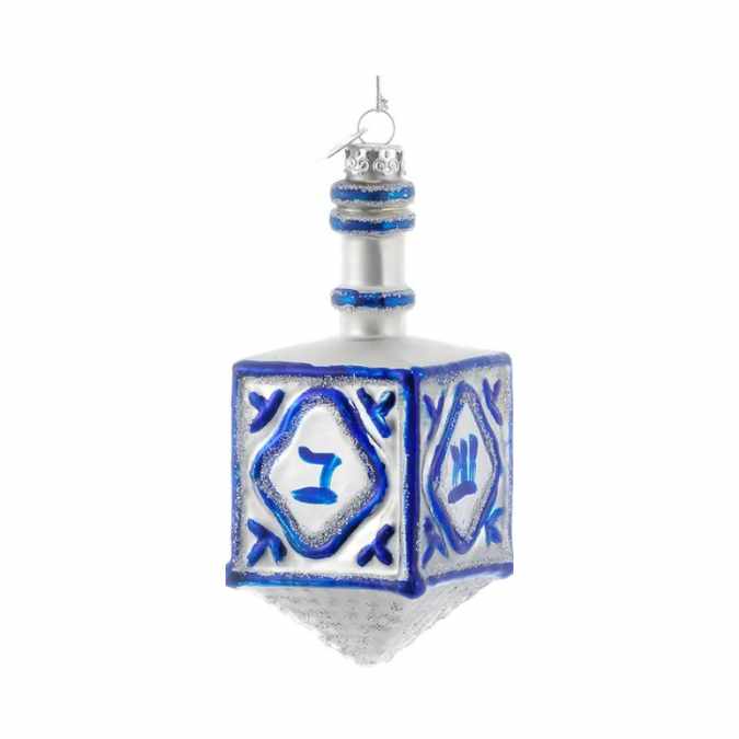 The Ornament - Dreidel from Available for Pick-Up & Delivery features a silver base, blue accents, and Hebrew letters—a festive glass ornament ideal for interfaith holiday décor.