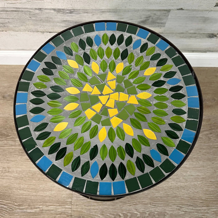 The All Delivery Options Plant Stand features a 19.5-inch round brown metal frame and a mosaic glass tabletop with blue, green, and yellow mandala-inspired design—ideal for indoor or outdoor use on any wood floor.