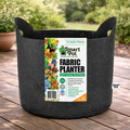 A 10-gallon Smart Pot fabric planter with handles from Available for Pickup & Delivery sits outdoors on a wooden surface. Its label lists features, while green grass and plants are visible in the background.