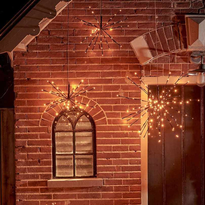 Three Polestar Flashing LED 72 ct. Black Decoration Classic Warm Lights glow warmly against a red brick wall near an arched window and door, creating a festive, cozy holiday ambiance with their classic warm white illumination.