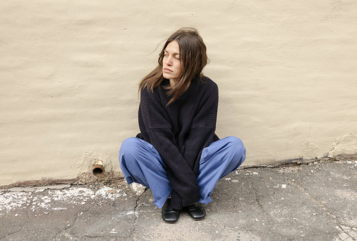 Person sitting on a concrete floor against a beige wall