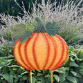 The Pumpkin Garden Stake – 32” by Available for Pick-Up & Delivery showcases a large, decorative pumpkin with vibrant orange hues and green leaves among lush lavender and greenery, adding rustic charm to your autumn garden decor.
