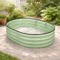 The Pick-Up & Local Delivery Only Raised Bed - Oval - Green, made of galvanized steel with a ribbed texture and internal support bars, sits on a stone patio surrounded by potted plants and greenery.