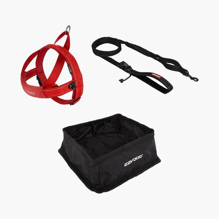 Red dog harness, black leash, and black dog bowl on a white background