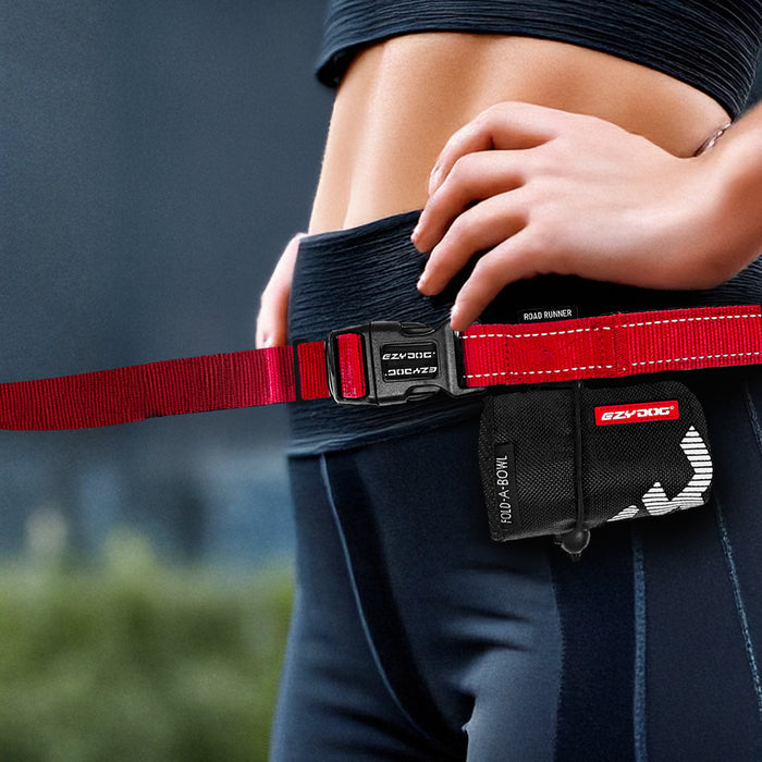 Person wearing a black and red dog leash with 'EzyDog' branding, against a blurred natural background.