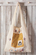 Embroidered tote bag with a design of a dress and heart shapes hanging on a wooden wall.