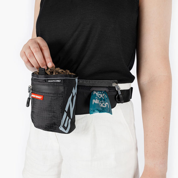 Person wearing a black waist bag with multiple pockets on a white background
