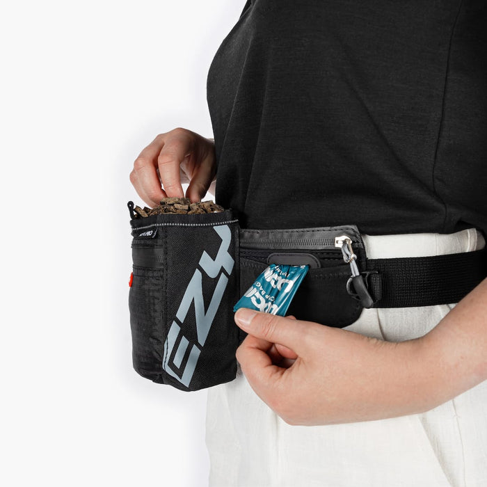 Person wearing a black waist bag with visible branding on a white background